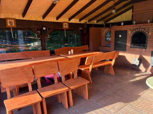 a restaurant with wooden tables and wooden chairs at Domek Pod Cisem na wyłączność in Kierzkowo
