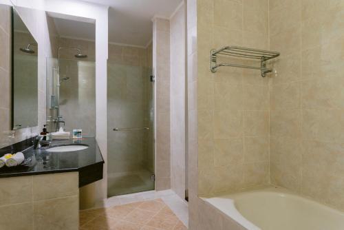 a bathroom with a tub and a sink and a shower at Legong Keraton Beach Hotel in Canggu