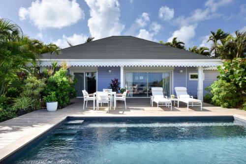a patio with a table and chairs next to a swimming pool at Rosewood Le Guanahani St Barth in Marigot