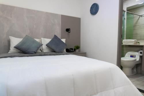 a bedroom with a large white bed and a toilet at ApartaHotel Estadio in Medellín