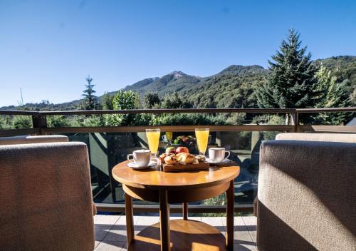 a table with a plate of food and drinks on a balcony at La Comarca Resort & Spa in Villa La Angostura