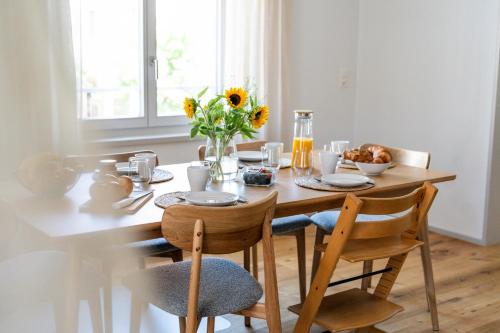 a dining room table with a vase of sunflowers at SOLUNA STAY I See & Berge I Luzern I Familienfreundlich I Ski I Self-check-in I Free Parking in Küssnacht