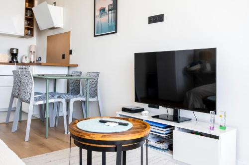 a living room with a large television and a table at Vue Panoramique sur Bassin,Piscine et terrasse in Arcachon