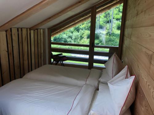 a bed with pillows in a room with a window at Lärchenwirt Dolomites in San Nicolò di Comelico