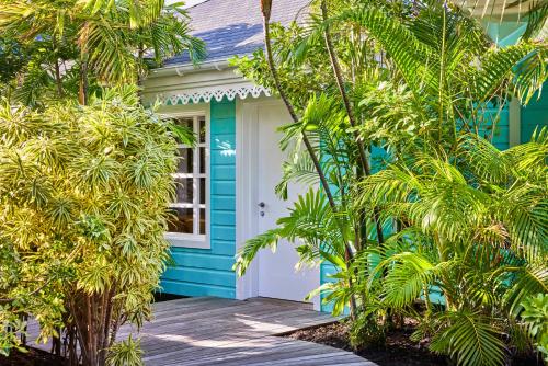 a blue house with a white door and trees at Rosewood Le Guanahani St Barth in Marigot