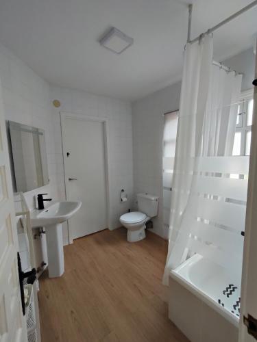 a white bathroom with a toilet and a sink at Apartamento la morenuca in Potes