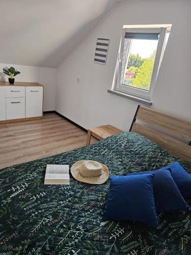 a bedroom with a bed with a hat on it at Zagajka SUN in Sarbinowo