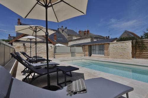 une piscine avec deux chaises et un parasol dans l'établissement Le Jardin d'Anatole : Parking / Haut Standing, à Châteauroux