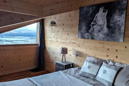 a bedroom with a bed and a large window at Chalet Cosy avec vue imprenable sur le lac in La Celle-sous-Gouzon