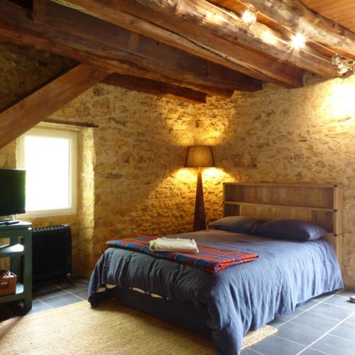 une chambre avec un lit dans un mur de pierre dans l'établissement Les choses de la vie, à Saint-Alvère