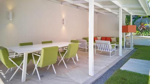 a patio with a white table and green chairs at AmazINN Places Luxury Villa El Cangrejo in Panama City