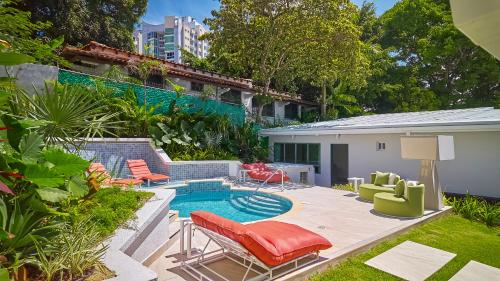 a backyard with a swimming pool with chairs and a table at AmazINN Places Luxury Villa El Cangrejo in Panama City