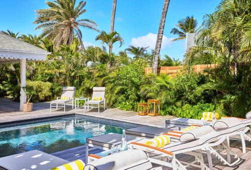 a pool with chaise lounge chairs and a swimming pool at Rosewood Le Guanahani St Barth in Marigot