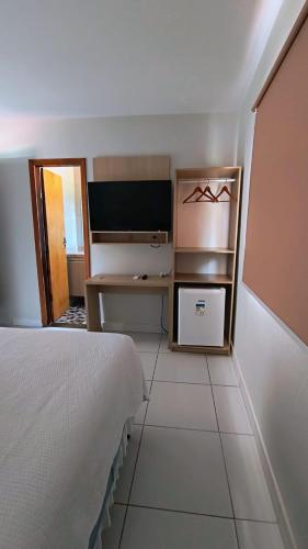 a bedroom with a bed and a desk and a television at Pousada HAI in Fernando de Noronha