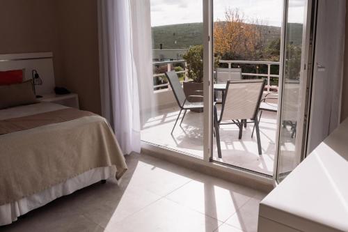 a bedroom with a bed and a balcony with a table and chairs at Altos de Tandil Hotel Boutique & Spa in Tandil