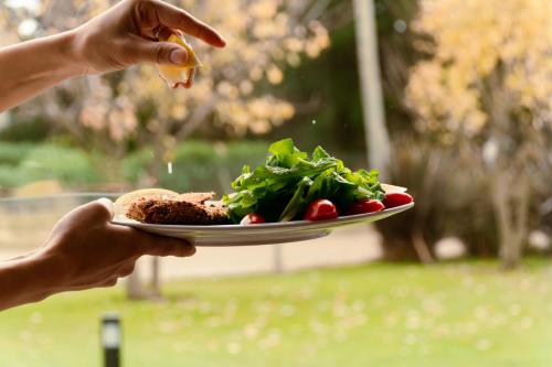 a person holding a plate with a plate of food at Altos de Tandil Hotel Boutique & Spa in Tandil