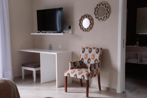 a room with a chair and a desk and a television at Altos de Tandil Hotel Boutique & Spa in Tandil
