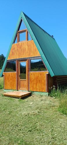 a house with a gambrel roof on a field at Etno SELO Uskoci in Uskoci