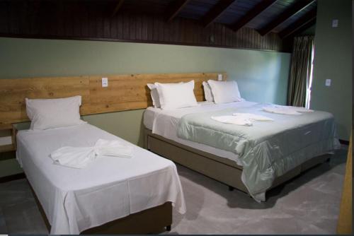 two beds in a hotel room with white sheets at Pousada Casarão Gastehaus in Pomerode