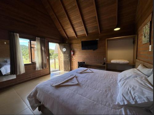 a bedroom with a large bed and a television at Pousada Casarão Gastehaus in Pomerode