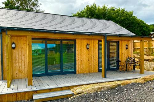 a wooden cabin with glass doors and a table on a deck at The Jeep House in the Area of Outstanding Natural Beauty in Liskeard