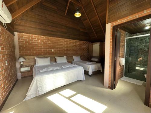 a bedroom with two beds and a brick wall at Pousada Casarão Gastehaus in Pomerode