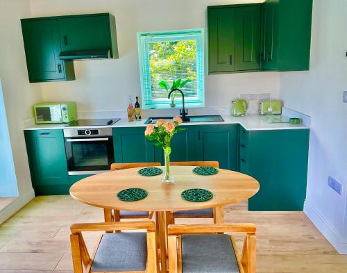 a kitchen with green cabinets and a wooden table at The Jeep House in the Area of Outstanding Natural Beauty in Liskeard