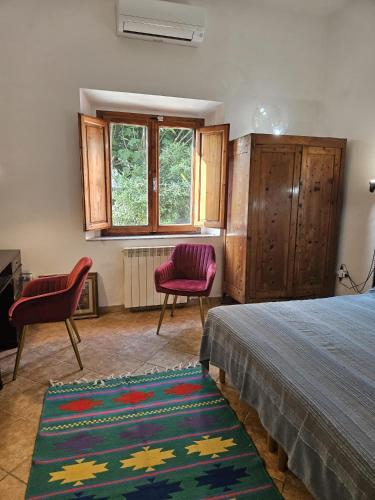 a bedroom with a bed and two chairs and a window at A garden on the bay in Castiglioncello