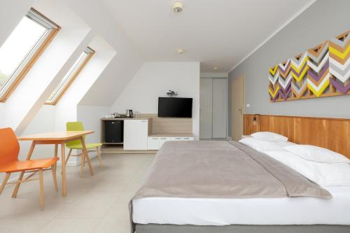 a bedroom with a bed and a table and chairs at Na Fali Restaurant&Apartaments in Pobierowo