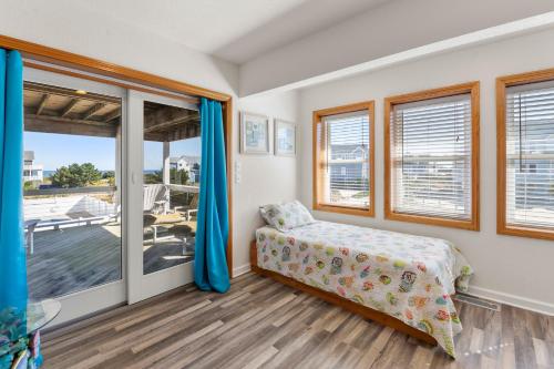 a bedroom with a bed and a balcony at SeaClusion in Corolla