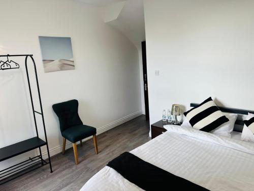 a bedroom with a bed and a chair at Sterling Bed & Breakfast in Ilford