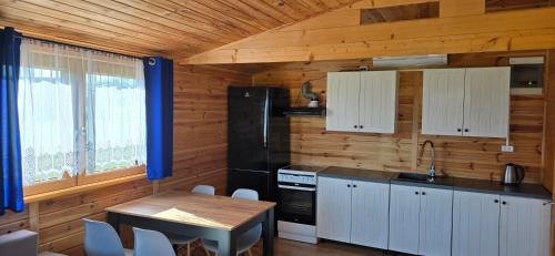 a kitchen with white cabinets and a wooden wall at Domek nad jeziorem Weekend in Swiętajno