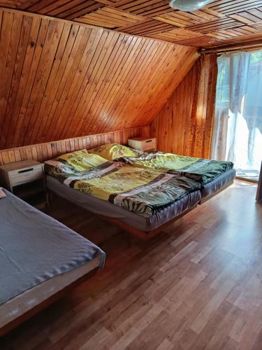 two beds in a room with a wooden wall at Chata Carla in Žiar