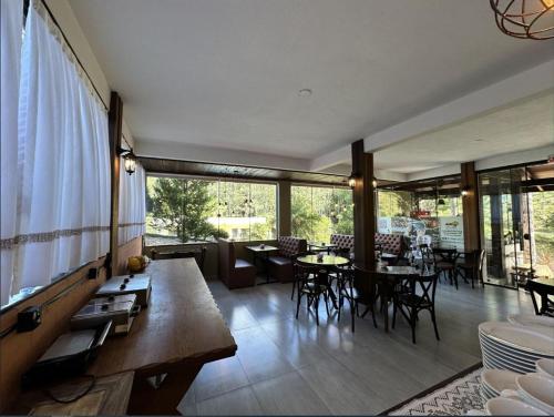 a living room with tables and chairs and windows at Pousada Casarão Gastehaus in Pomerode