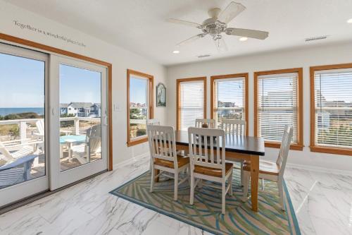 a dining room with a table and chairs and windows at SeaClusion in Corolla