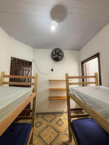 a room with two beds and a clock on the wall at Casa Maria Flor Guest House in Itacaré
