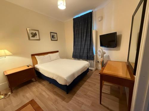 a hotel room with a bed and a television at The Elder Guest House in Epsom