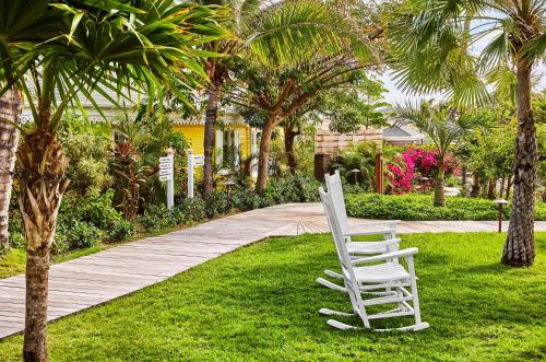 a white chair sitting on the grass next to a walkway at Rosewood Le Guanahani St Barth in Marigot