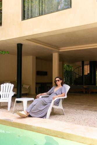 a woman sitting in a chair next to a pool at Pent House - Santuario Apartments in Chemuyil