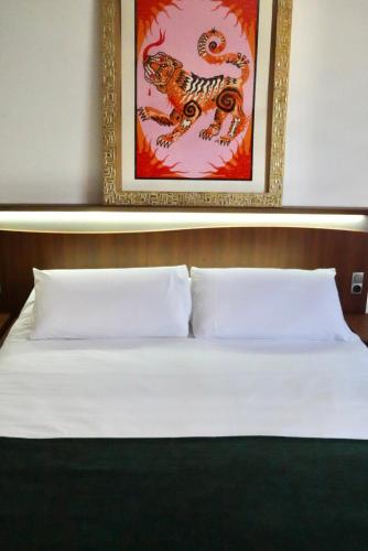 a bedroom with a white bed with a painting on the wall at Chambre confort - Le Boudoir in Hendaye