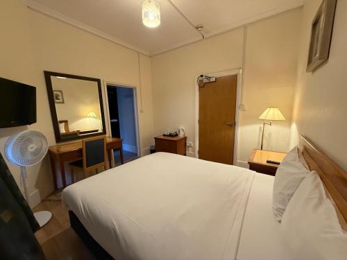 a hotel room with a bed and a desk and a mirror at The Elder Guest House in Epsom