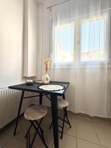 a black table with two chairs and a vase on it at Olea Central Stay in Nea Kalikratia