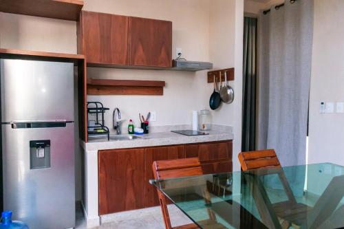 a kitchen with a glass table and a refrigerator at Pent House - Santuario Apartments in Chemuyil