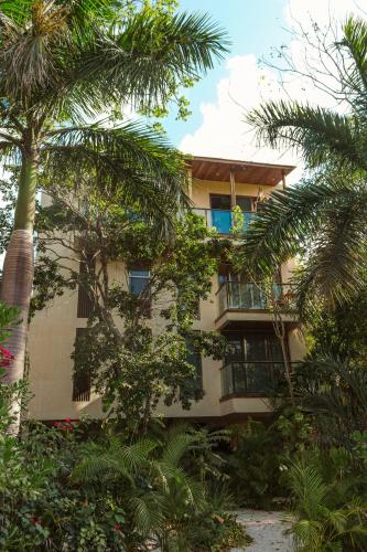 a building with palm trees in front of it at Pent House - Santuario Apartments in Chemuyil