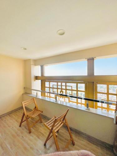 two wooden chairs in a room with a balcony at Gold Crest Mall Prestigious Suites with Balcony by CityScape in DHA Lahore in Lahore