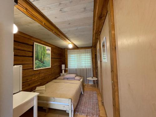 a bedroom with two beds in a room with wooden walls at Lauku viesnīciņa KLĒTS VIJĀS in Degumuiža