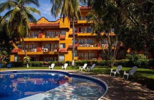 a hotel with a swimming pool in front of a building at Villa Hotel Puerta del Mar in Ixtapa