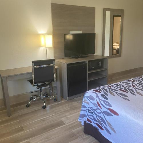 a hotel room with a bed and a desk and a television at Red Roof Inn Queensbury in Queensbury