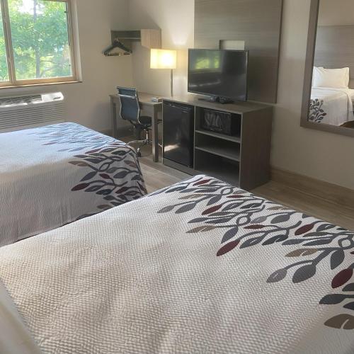 a hotel room with a bed and a flat screen tv at Red Roof Inn Queensbury in Queensbury