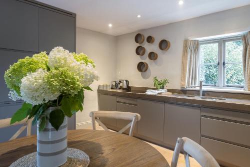 a kitchen with a table with a vase of flowers at Lilycombe Farm in Bath